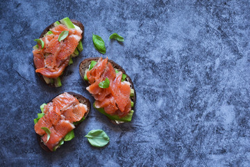 Sandwich with avocado and salmon on a concrete background. View from above.