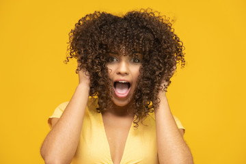 Happy laughing American African woman with her curly hair on yellow background. Laughing curly...