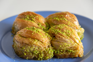 Turkish Midye Baklava ( Mussel Shaped Baklava ) with Green Pistachio Powder and Butter Cream. Turkish   baklava on blue dish