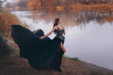 Beautiful attractive woman dark queen walks by river. Art photography. Princess warrior creative...
