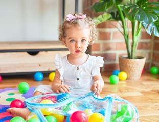 Fototapeta na wymiar Beautiful caucasian infant playing with toys at colorful playroom. Happy and playful wth colorful balls at kindergarten.
