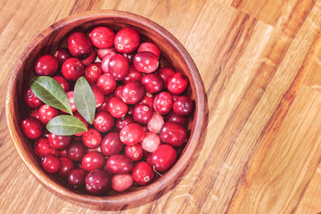 ripe fresh cranberries in a wooden bowl close-up view from above. background with fresh cranberries.
