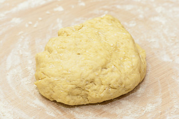 Fototapeta na wymiar A piece of dough on a table strewn with flour