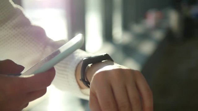 A sports girl monitors health problems with a smart watch. Close-up hand holding a phone and smart watch. Modern technology and a healthy lifestyle.