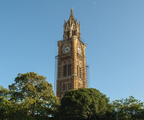 Fototapeta na wymiar The old, British-era Rajabai Clock Tower in the city of Mumbai with scaffolding around it for restoration and repairs.