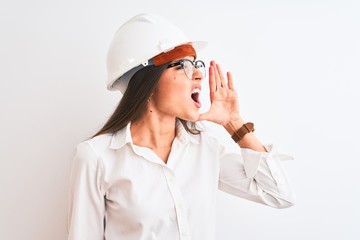 Young beautiful architect woman wearing helmet and glasses over isolated white background shouting and screaming loud to side with hand on mouth. Communication concept.