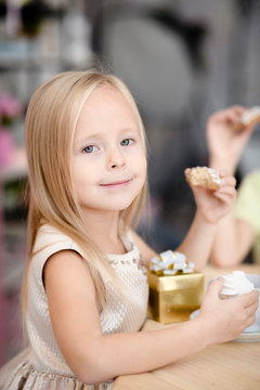 Portrait Of Smiling Little Girl With Gift Box Eating Cookies