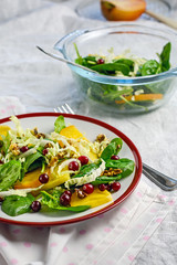 Salad with persimmons, spinach, walnuts and cranberries.