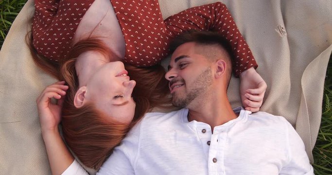 Happy young couple lying on picnic blanket, above view