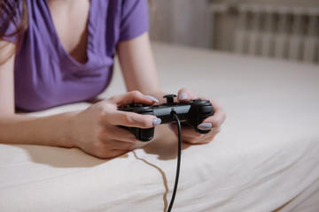 Girl gamer plays with a gamepad while looking at the screen in front of her.