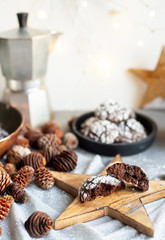 Fototapeta premium Home baked chocolate crinkle cookies in icing sugar. Cracked chocolate biscuits in a white plate on Christmas background. Chocolate Christmas brown cookies in powdered sugar with cracks. Copy space.