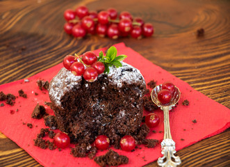 halbes schokoladenmuffin mit puderzucker und johannisbeeren dekoriert
