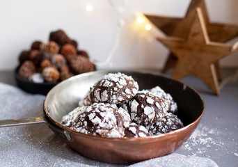 Home baked chocolate crinkle cookies in icing sugar.  Cracked chocolate biscuits in a copper pan on Christmas background. Chocolate Christmas brown cookies in powdered sugar with cracks. Copy space.