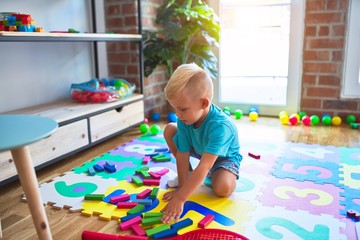 Young caucasian kid playing at kindergarten with toys. Preschooler boy happy at playroom.