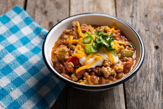Texmex dish called "Chili con carne" with cheese and sour cream on wooden background