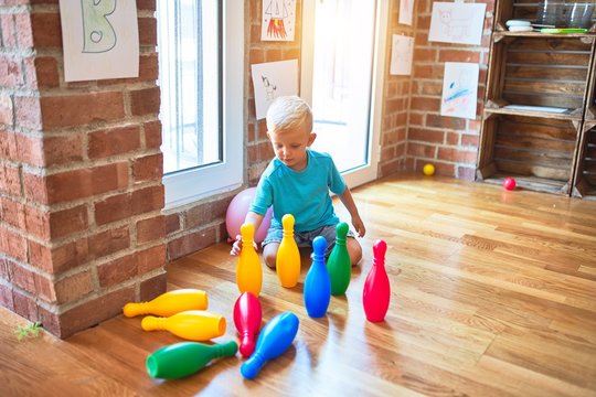 Young caucasian kid playing at kindergarten with toys. Preschooler boy happy at playroom.