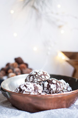 Home baked chocolate crinkle cookies in icing sugar.  Cracked chocolate biscuits in a copper pan on Christmas background. Chocolate Christmas brown cookies in powdered sugar with cracks. Copy space.