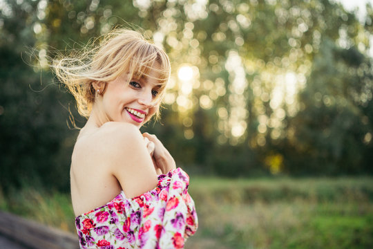 Portrait of happy young woman wearing summer dress with floral design in nature