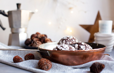 Home baked chocolate crinkle cookies in icing sugar.  Cracked chocolate biscuits in a copper pan on Christmas background. Chocolate Christmas brown cookies in powdered sugar with cracks. Copy space.