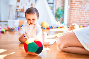 Fototapeta premium Beautiful infant happy at kindergarten around colorful toys
