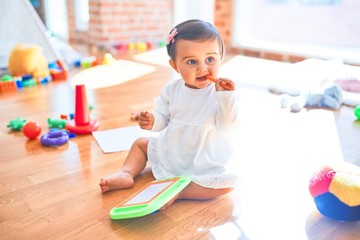Beautiful infant happy at kindergarten around colorful toys drawing on magnetic blackboard