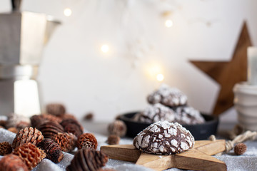 Home baked chocolate crinkle cookies in icing sugar.  Cracked chocolate biscuits in a white plate on Christmas background. Chocolate Christmas brown cookies in powdered sugar with cracks. Copy space.