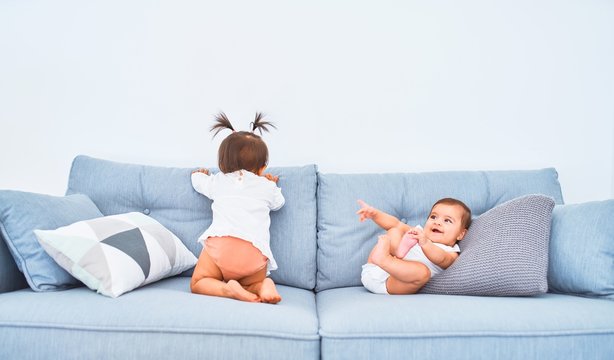 Beautiful infant happy girls playing together at home kindergarten sitting on the sofa