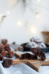 Home baked chocolate crinkle cookies in icing sugar.  Cracked chocolate biscuits in a white plate on Christmas background. Chocolate Christmas brown cookies in powdered sugar with cracks. Copy space.