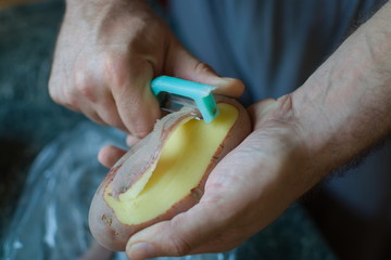 closeup of hands peeling a potato