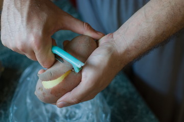 closeup of hands peeling a potato