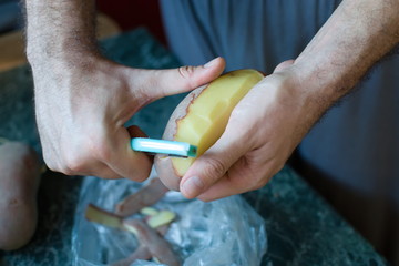 closeup of hands peeling a potato