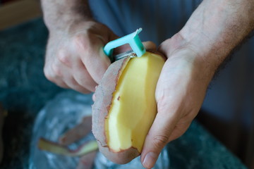 closeup of hands peeling a potato