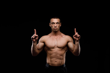 Sexy torso. Muscular model sports young man in jeans showing his press on a black background. Fashion portrait of sporty healthy strong muscle guy. 