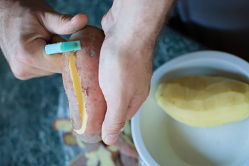 closeup of hands peeling a potato