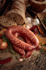Dry-cured sausage with bread and spices on a old wooden table.