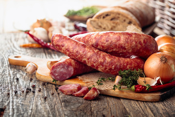 Dry-cured sausage with bread and spices on a old wooden table.