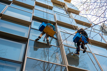 Workers washes windows of a building hanging on a ropes.