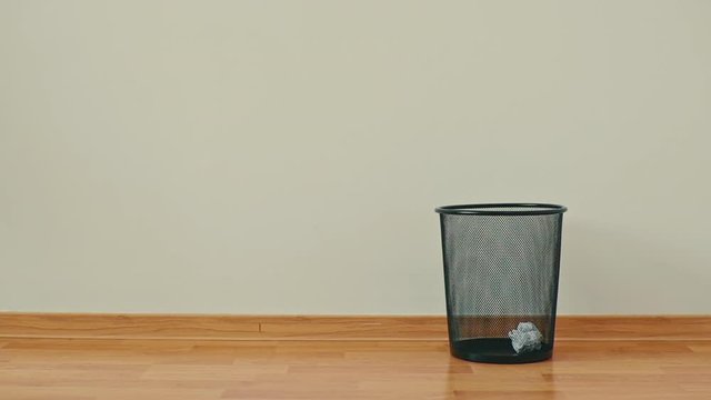 Throwing away unwanted paper in an empty trash can in the office.