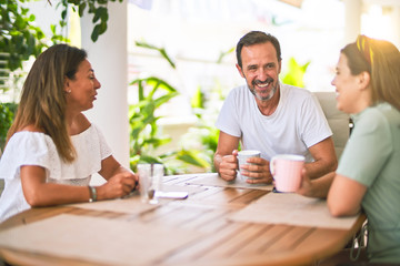 Beautiful family sitting on terrace drinking cup of coffee speaking and smiling