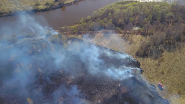 Aerial view of smoking wild fire. Dry grass burning in the field, drone footage