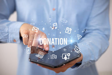 Businessman holding a foldable smartphone with DONATION inscription, social media concept
