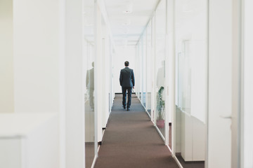 Rear view of businessman walking down office corridor