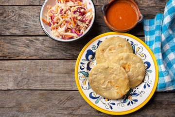 Salvadoran pupusas with coleslaw and tomato sauce on wooden background