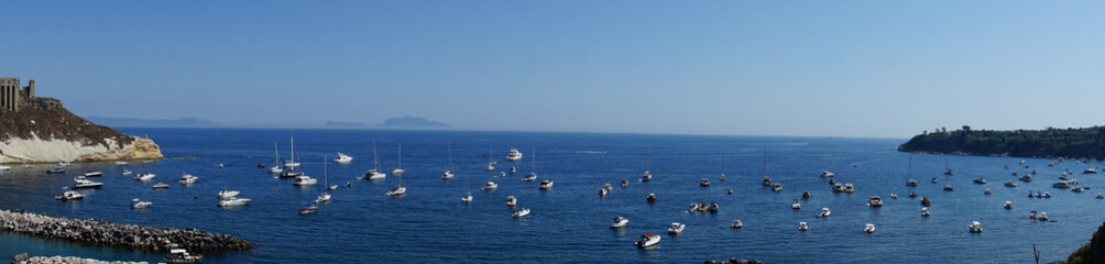 Obraz premium Panoramic view of fishing boats and yachts, clear blue sky and the azure sea on the island of Procida, Italy. Near Napoli