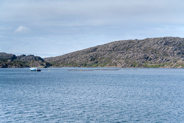 Fototapeta na wymiar fish farm and rocky shore at fjord island, Ytre Sula, Norway