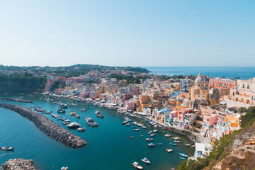 Panoramic view of beautiful Procida on a sunny summer day. Colorful cafes, houses and restaurants, fishing boats and yachts, clear blue sky and the azure sea on the island of Procida, Italy. Napoli