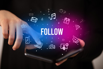 Businessman holding a foldable smartphone with FOLLOW inscription, social media concept