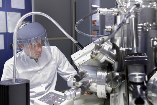 Scientist sitting in analytical laboratory with scanning electron microscope and spectrometer