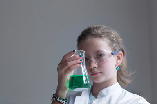 Female pupil holding glass with green reagent