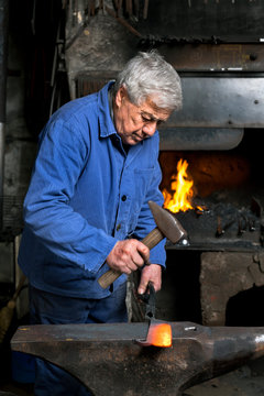 Germany, Bavaria, Josefsthal, blacksmith working on billhook at historic blacksmith's shop